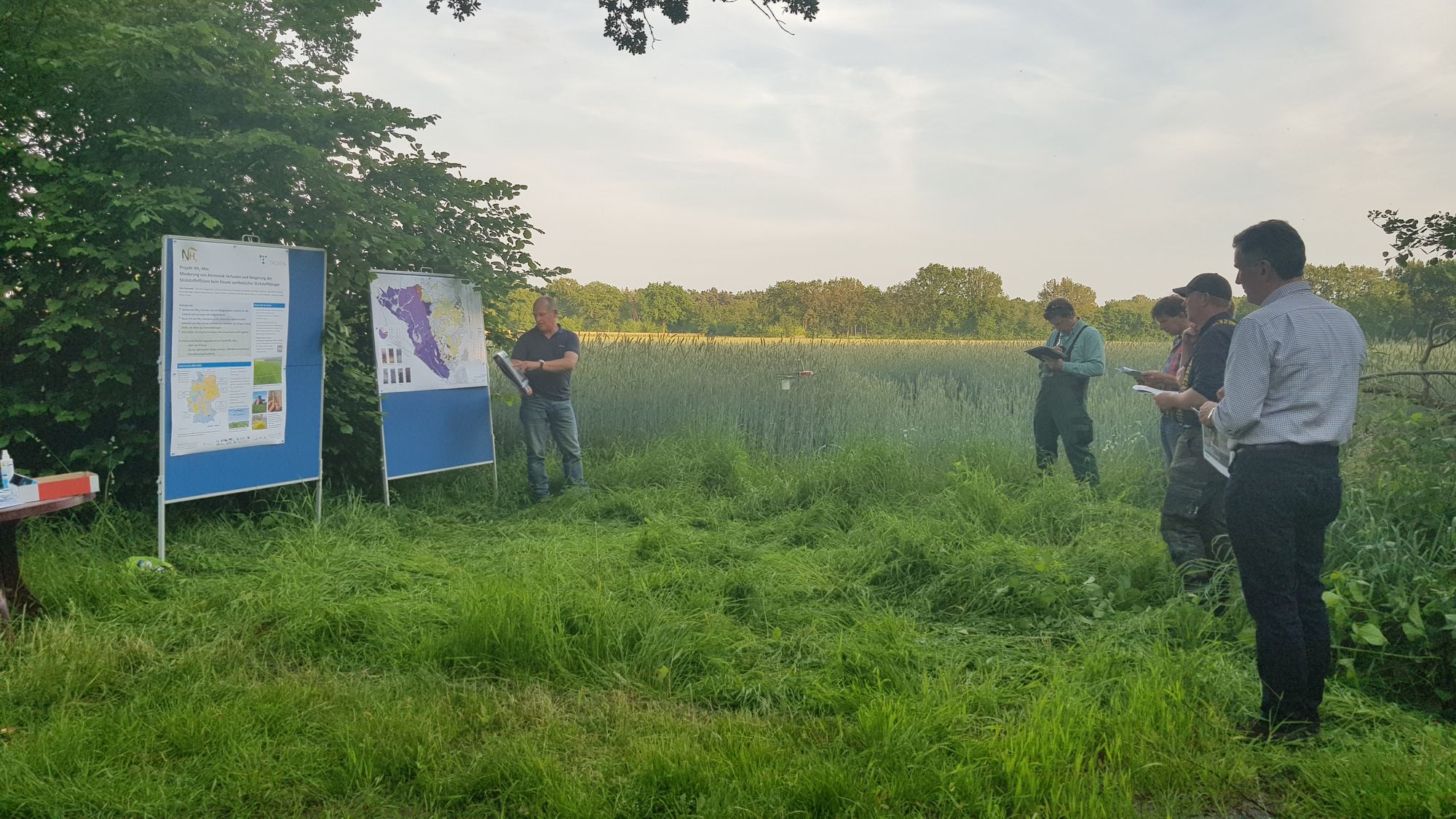 Das Bild zeigt Poster auf dem Feldtag in der Haseldorfer Marsch vor einem Versuchsfeld